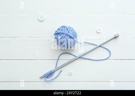 Yarn ball, knitting needles and buttons on white wooden background Stock Photo