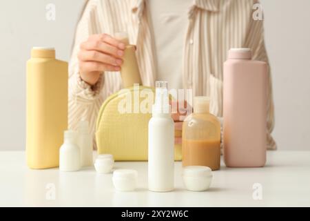Woman with different travel cosmetic products at light table Stock Photo