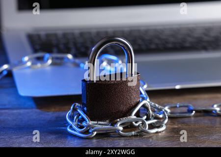 Padlock with chain and laptop on table, closeup. Cyber security concept Stock Photo