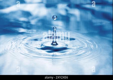 Drops of water fall onto the water surface Stock Photo
