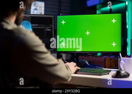 Developer updating artificial intelligence machine learning algorithm on isolated screen PC desktop. IT specialist in apartment office uses programming to upgrade AI on chroma key monitor Stock Photo
