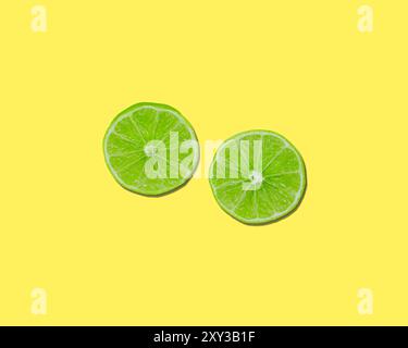 Green lime halves sliced on lemon yellow background Stock Photo