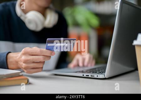 A close-up image of a man holding a credit card over a table while using his laptop. online shopping, online money transferring, online payment Stock Photo