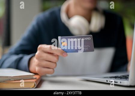 A close-up image of a man holding a credit card over a table while using his laptop. online shopping, online money transferring, online payment Stock Photo