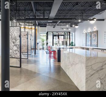 View toward front door of marble and stone showroom with large slabs on display and Calacatta marble island Stock Photo