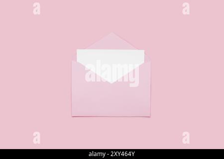Closeup on blank empty white paper card in pink opened envelope isolated on pink pastel color background. Love letter minimal concept. Conceptual layo Stock Photo
