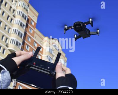 Quadrocopter flies in the sky and hands with a control panel Stock Photo