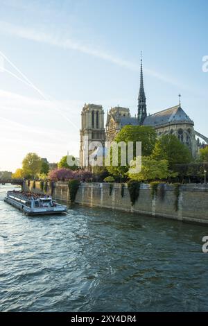 Seine River tourist boat passing rear of Notre Dame Cathedral during springtime in Paris, France, Europe Stock Photo