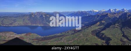 Landscape in the Bernese Oberland. Lake Thunersee. Distant view of Eiger, Monch and Jungfrau. Villages Spiez, Aeschi and Aeschiried. Shadow of mount N Stock Photo