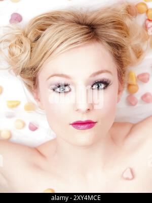 Portrait of a young blonde woman lying between sweets Stock Photo