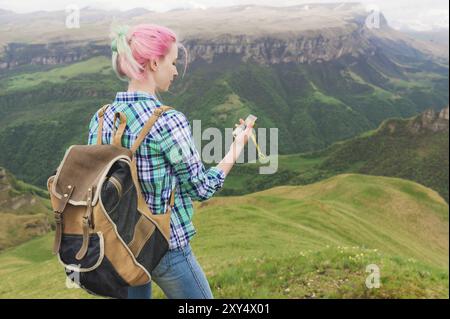 A hipster girl traveled with a blogger in a plaid shirt and with multi-colored hair using a compass in the background in the background of the Caucasi Stock Photo