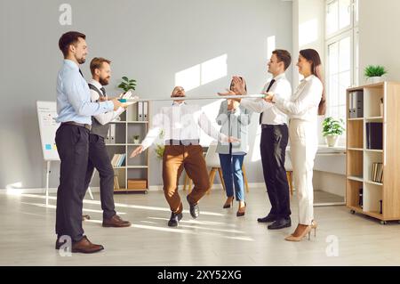 Office Workers Playing Limbo And Dancing At Office Party Stock Photo