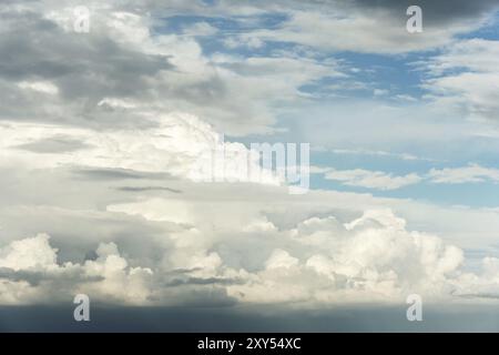 Large (Cumulus) cloud before the rain in the evening at sunset. The cloud is illuminated by the evening sunlight. Dangerous weather before rain or thu Stock Photo