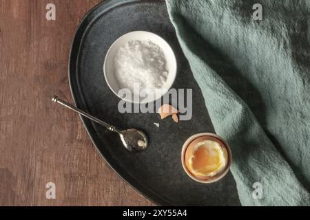 A soft-boiled egg in an egg server with coarse sea salt and a spoon, shot from the top with a place for text Stock Photo