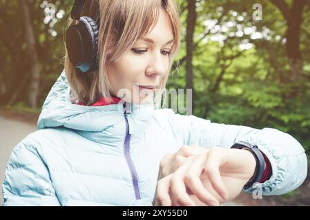 Portrait Young fitness woman looking at her smart watch while taking a break from sports training. Sportswoman checking pulse on fitness smart watch d Stock Photo