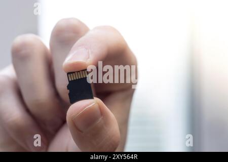 Young man is holding a tiny memory card in his hand, text space Stock Photo