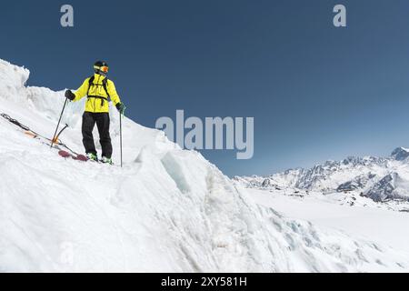 A freerider skier in complete outfit stands on a glacier in the North Caucasus against the background of the Caucasian snow-capped mountains Stock Photo