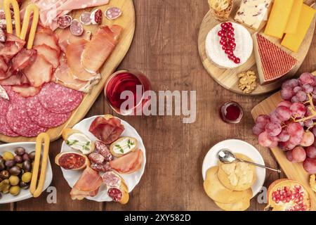 Charcuterie Tasting. A photo of many different hams, lunch meats, and a cheese platter, shot from the top on a rustic background with a glass of red w Stock Photo