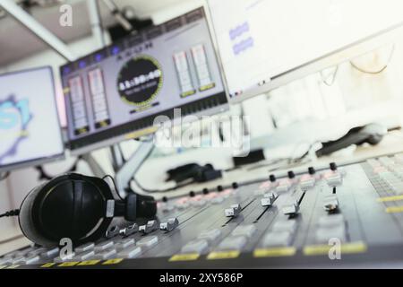Close up picture of a soundboard in a broadcasting studio, computers in the blurry background Stock Photo