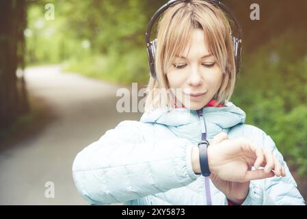 Portrait Young fitness woman looking at her smart watch while taking a break from sports training. Sportswoman checking pulse on fitness smart watch d Stock Photo