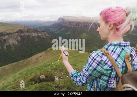 A hipster girl traveled with a blogger in a plaid shirt and with multi-colored hair using a compass in the background in the background of the Caucasi Stock Photo
