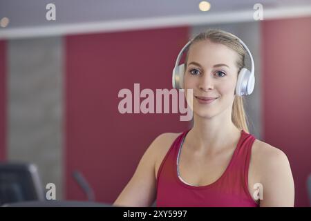 Smiling young blond woman wearing headphone in gym Stock Photo