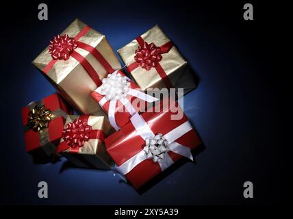 Pile of Christmas gift boxes illuminated in darkness isolated on dark blue background Stock Photo