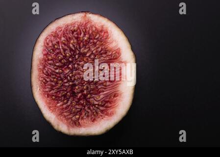 Cut in half fresh fig isolated on black background. Detailed macro shoot. Copy space Stock Photo