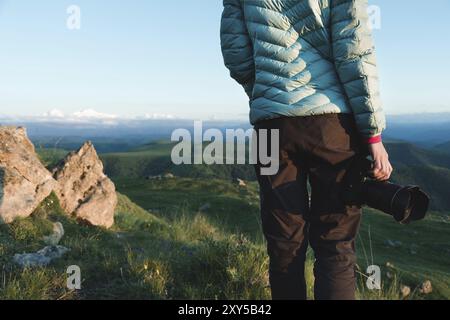 Photos on the shoulders behind the girl photographer in nature with a camera in hand. Back view Stock Photo