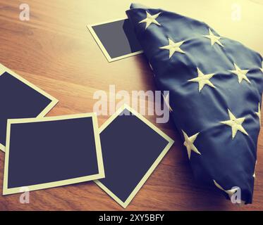 Old photo frames with a folded American flag on a wooden table Stock Photo