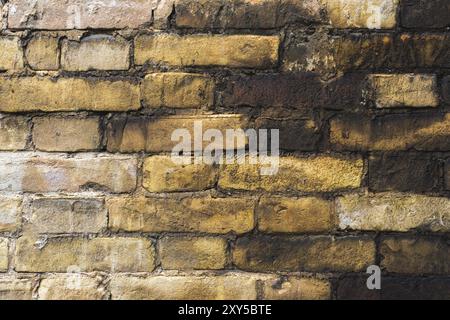 Textured background of old faded bricks stained with black oil. A brick gradient between dirty black and light yellow bricks. Grunge style Stock Photo