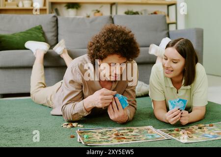 Couple Relaxing On Floor And Playing Board Game Stock Photo