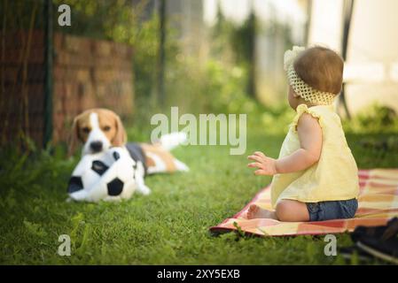 Young baby girl with a beagle dog outdoors. Family pet concept Stock Photo