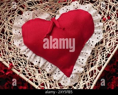 Red fabric heart shape on red shredded paper, love concepts Valentines Day or Mothers Day background Stock Photo