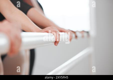 People, hands and ballet dancers with balance on barre for lesson or class in row, line or studio. Closeup of female person or ballerina group leaning Stock Photo