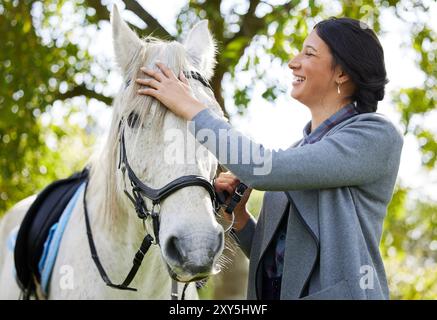 Rider, woman and laughing with horse in forest for companion, fun training and relax from practice. Equestrian, happy person or stallion in Stock Photo