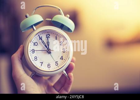 Man is holding an alarm clock, sunshine in the morning, blurry background Stock Photo