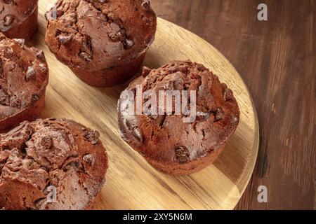 A closeup photo of chocolate muffins on a dark rustic wooden background with copy space Stock Photo