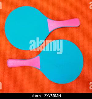 Above, ping pong or bats in studio for fitness, fun or retro aesthetic on orange background. Olympic sport, paddles or opposed on textured backdrop in Stock Photo