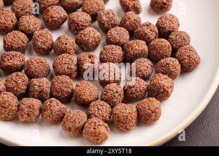 Cereal brown chocolate balls or crunchy breakfast corn flakes in kitchen ceramic plate. Stock Photo