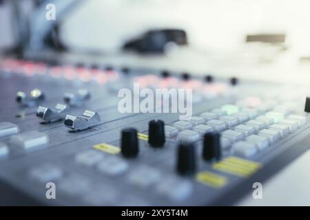 Close up picture of a soundboard in a broadcasting studio, computers in the blurry background Stock Photo