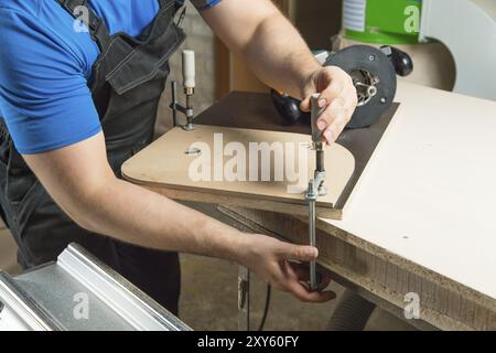 Close up Master clamps the workpiece with a dvp clamp to the workbench and on the background lies Carpentry hand router Stock Photo