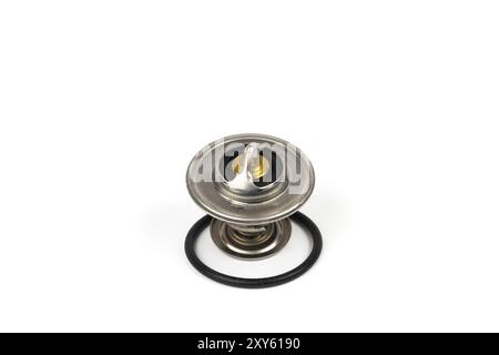 New car thermostat on a white isolated background next to a rubber gasket. Repair kit of spare parts for the replacement of the thermostat in the engi Stock Photo