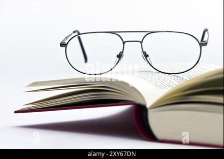 Reading glasses on open book pages Stock Photo