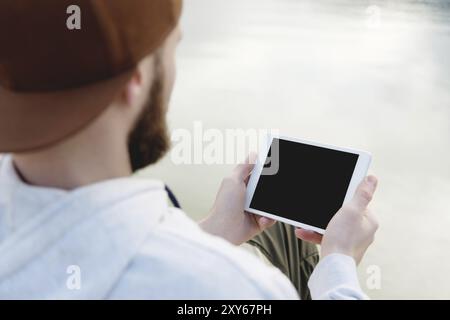 Hipster person holding in hands digital tablet with empty blank screen, man photograph on computer on background nature outdoor landscape mock up tech Stock Photo