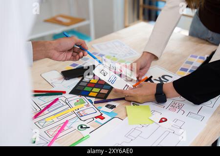 Creative Team Collaborating on UX UI Design with Colorful Prototypes and Wireframes on a Wooden Desk Stock Photo