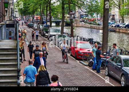 AMSTERDAM, NETHERLANDS - JULY 10, 2017: People visit Herengracht canal in Amsterdam, Netherlands. Amsterdam is the capital city of The Netherlands. Stock Photo