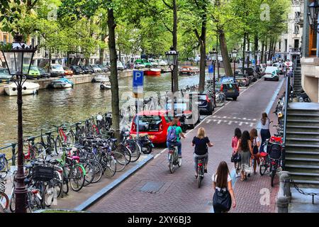 AMSTERDAM, NETHERLANDS - JULY 10, 2017: People visit Herengracht canal in Amsterdam, Netherlands. Amsterdam is the capital city of The Netherlands. Stock Photo