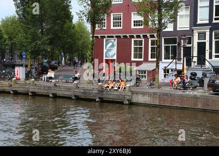 AMSTERDAM, NETHERLANDS - JULY 10, 2017: People visit Herengracht canal in Amsterdam, Netherlands. Amsterdam is the capital city of The Netherlands. Stock Photo