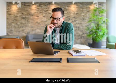 Portrait of confident web designer in glasses developing computer software at desk in modern office Stock Photo